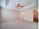 Spacious main bedroom featuring a tray ceiling with ceiling fan and neutral carpeting at 7524 Common Oak Dr, Stanley, NC 28164
