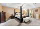 Spacious main bedroom with four-poster bed, tray ceiling, and a cozy sitting area by the window at 8619 Delamere Ln, Charlotte, NC 28269