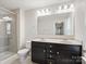 Bathroom featuring double sinks with granite countertops, dark cabinets, and a glass-enclosed shower at 105 Elk Ct, Mount Holly, NC 28120
