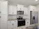 This modern kitchen features white cabinets, granite countertops, stainless steel appliances and luxury vinyl plank flooring at 105 Elk Ct, Mount Holly, NC 28120