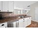 Galley kitchen with stainless steel dishwasher, white cabinetry, and views to the dining room at 113 Devynn Ridge Ct, Mount Holly, NC 28120