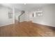 Open-concept room with hardwood floors, neutral walls, and staircase at 113 Devynn Ridge Ct, Mount Holly, NC 28120