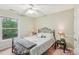 A cozy bedroom featuring a metal frame bed, ceiling fan, and a window overlooking the greenery outside at 11333 Snapfinger Dr, Charlotte, NC 28277