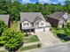 Aerial view of a two-story home featuring a three-car garage, well manicured lawn, and lush landscaping at 128 Front Porch Dr, Rock Hill, SC 29732