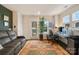 Bright living room with a door leading to an outdoor space, a brown leather sofa, and a computer desk at 15041 New Amsterdam Ln, Charlotte, NC 28204