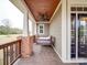 Front porch featuring a bed swing, wood ceiling, brick columns, and black front door at 15211 Windward Ln, Lancaster, SC 29720