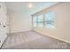 An empty bedroom with three windows and light-grey carpet, offers a peaceful and bright living space at 1526 Cottage Creek Dr, Bessemer City, NC 28016