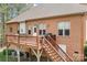 Exterior deck of brick home with wooden stairs, railing, and door to access the home at 164 Crooked Branch Way, Troutman, NC 28166