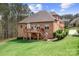 Brick home with large wooden deck and stairs. Features a manicured lawn with green grass at 164 Crooked Branch Way, Troutman, NC 28166