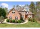 Brick home featuring a well-manicured lawn, mature trees, and a welcoming front entrance at 164 Crooked Branch Way, Troutman, NC 28166