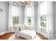 Bright sitting area with a chaise lounge and arched windows overlooking the landscaped outdoors at 164 Crooked Branch Way, Troutman, NC 28166