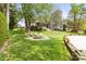 Picturesque backyard with fire pit, mature trees, stone terracing, and green lawn at 19040 Mary Ardrey Cir, Cornelius, NC 28031