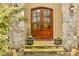 Inviting entryway with double wooden doors, stone accents, and decorative potted plants at 19040 Mary Ardrey Cir, Cornelius, NC 28031