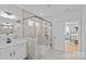 Bathroom with glass shower, tile, dual sink vanity, cabinets, and view to the primary bedroom at 2017 Autumn Dr, Monroe, NC 28110
