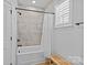 Bathroom featuring tile-surround tub/shower with neutral walls and a wooden seat near a window at 2017 Autumn Dr, Monroe, NC 28110