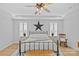 Bright and airy bedroom showcasing tray ceiling, hardwood floors, shutters, and a cozy seating area at 2017 Autumn Dr, Monroe, NC 28110