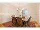 An elegant dining room featuring a chandelier, wainscoting, hardwood floors, and a red oriental rug at 20635 Queensdale Dr, Cornelius, NC 28031