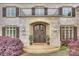 Grand stone entrance showcasing an arched doorway, double doors, elegant lighting, and landscaped foliage at 20635 Queensdale Dr, Cornelius, NC 28031