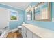 Bright bathroom with blue walls, vanity with a large mirror, and a window with a view of greenery at 2300 Linwood Rd, Gastonia, NC 28052