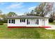 Charming single-story home features a red accent and black shutters, nestled among mature trees and a lush lawn at 2300 Linwood Rd, Gastonia, NC 28052