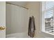 Neutral bathroom showcasing a tub with shower, curtain rod, and a sun-filled window at 2812 Edgebrook Cir, Matthews, NC 28105