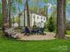 This brick firepit area with wooden chairs is set amongst the trees creating a charming backyard space at 2812 Edgebrook Cir, Matthews, NC 28105