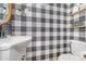 Stylish powder room featuring black and white checkered wallpaper, toilet, and sink at 511 Plymouth Ave, Salisbury, NC 28144