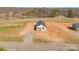 Expansive aerial view of a quaint white home with a dark roof, surrounded by undeveloped land and clear blue skies at 603 Mt. Wesley Church Rd, Hiddenite, NC 28636