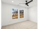 Bright bedroom featuring neutral carpet, a ceiling fan, and double windows overlooking wooded property at 605 Arrow Point Ln, Davidson, NC 28036