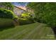 Expansive backyard featuring stone retaining walls, lush greenery, and access stairs at 6804 Riesman Ln, Charlotte, NC 28210