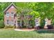 Charming two-story brick home with manicured lawn, mature trees, and inviting front entrance at 6804 Riesman Ln, Charlotte, NC 28210