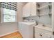 Bright laundry room with modern washer and dryer, storage cabinets and sink at 6804 Riesman Ln, Charlotte, NC 28210