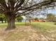 Spacious backyard with mature trees, a wooden swing, and a tranquil seating area at 7514 Secrest Shortcut Rd, Indian Trail, NC 28079