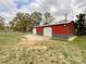 Large red barn with roll-up doors and gravel area, offering ample space for storage and rural activities at 7514 Secrest Shortcut Rd, Indian Trail, NC 28079
