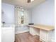 Bright laundry room with pale blue walls, wood floor and folding table by window with white and patterned curtains at 848 Woodland Rd, Statesville, NC 28677