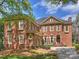 A beautiful red brick home with manicured landscaping, blue sky, and mature tree in this exterior elevation at 8912 Heydon Hall Cir, Charlotte, NC 28210