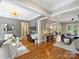 A well decorated living room with hardwood floors, gray wallpaper accent wall, and adjoining seating areas at 8912 Heydon Hall Cir, Charlotte, NC 28210