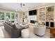 A comfortable living room with a fireplace, built-in bookcases, French doors, and a neutral color palette at 8912 Heydon Hall Cir, Charlotte, NC 28210