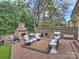 Inviting outdoor patio featuring a stone fireplace, built-in seating, grill and brick pavers perfect for entertaining at 8912 Heydon Hall Cir, Charlotte, NC 28210