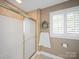 Shower featuring frosted glass door, window with plantation shutters, tile surround and neutral color scheme at 925 Lanier Ln, Monroe, NC 28110