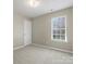 This bedroom has carpet, neutral walls, a large window, and white trim at 10107 Atkins Ridge Dr, Charlotte, NC 28213