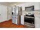 Modern kitchen with stainless steel appliances, wood floors, and sleek white cabinets at 10107 Atkins Ridge Dr, Charlotte, NC 28213