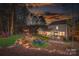 Night view of the landscaped backyard with a fire pit and patio area, perfect for evening gatherings and relaxation at 10823 Preservation Park Dr, Charlotte, NC 28214