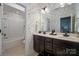 Bathroom featuring dual sinks, dark wood cabinets, and a shower-tub combo at 10823 Preservation Park Dr, Charlotte, NC 28214