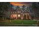 Dusk view of a charming brick two-story home with landscaped yard and warm exterior lighting at 10823 Preservation Park Dr, Charlotte, NC 28214