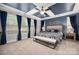 Relaxing primary bedroom with tray ceilings, a ceiling fan, large windows and neutral colored carpet at 10823 Preservation Park Dr, Charlotte, NC 28214