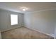 Neutral bedroom featuring beige carpet, a window for natural light, and freshly painted walls at 121 Silver Fox Ct, Mount Holly, NC 28120