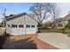Detached three-car garage with white doors, a brick driveway, and a basketball hoop in the backyard at 1212 Queens Rd, Charlotte, NC 28207