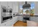 Contemporary kitchen featuring stainless steel appliances, white cabinetry, and hardwood floors at 1212 Queens Rd, Charlotte, NC 28207