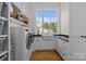 Well-lit laundry room with modern washer and dryer, sink, and custom white cabinets at 1212 Queens Rd, Charlotte, NC 28207
